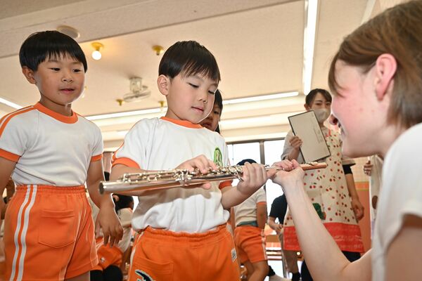 フルートの持ち方を学生から教わる園児ら