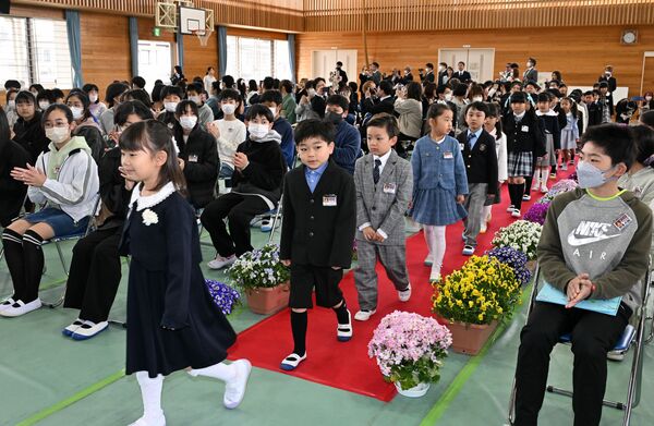 在校生や保護者の拍手の中で入学式に臨む新入生＝１０日午前９時２０分、今市第三小