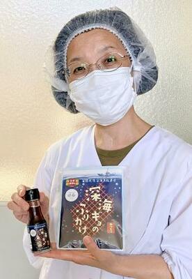　深海魚で作った魚醤とふりかけを手にする製造担当者の中西美智子さん＝愛知県蒲郡市