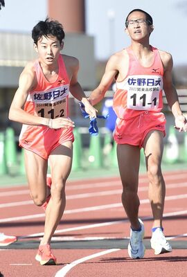 佐野日大の１区山口彰（右）からたすきを受けた２区大島が走り出す＝ひたちなか市総合運動公園陸上競技場