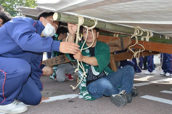 若衆から麻ひもの結び方を教わる生徒（左）