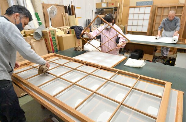 分担して手際よく障子を張り替える従業員たち＝７日午後０時10分、宇都宮市材木町