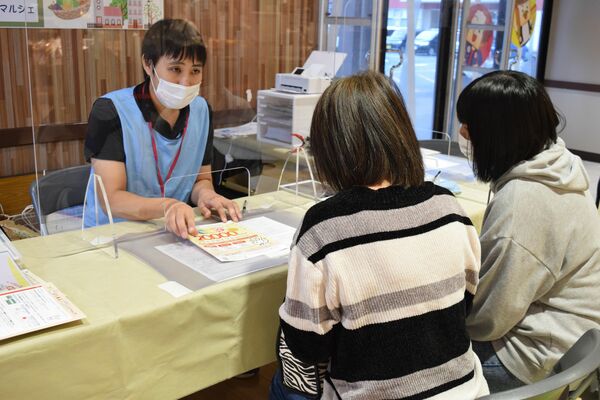 マイナンバーカードの出張申請サポートでスタッフに相談する親子連れ＝10日午後、小山市中久喜のイオンモール小山