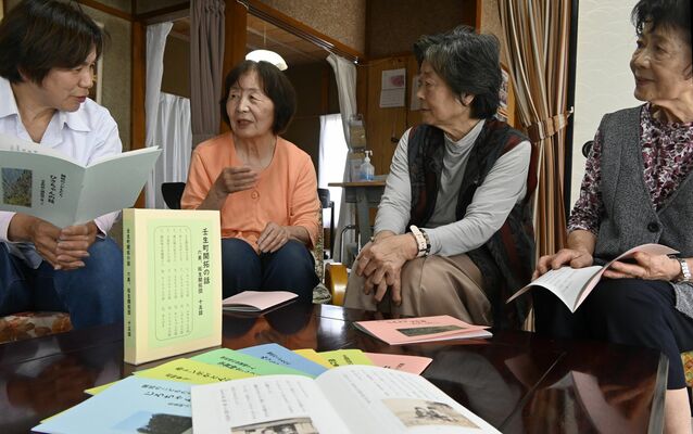 見本を手に取って冊子の中身を確認する会のメンバー＝５月中旬、壬生町壬生丁