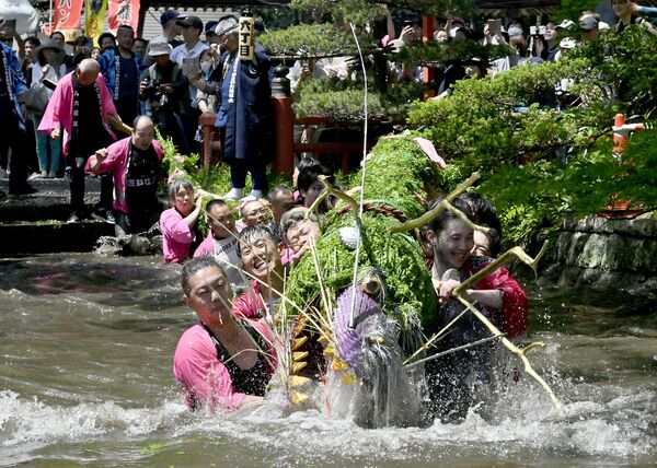 「水飲みの儀」で水しぶきを上げながら池を進む大蛇＝５日午後０時25分、小山市間々田