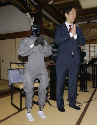 仏教経典を学習した生成AIを搭載した人型ロボット「ブッダロイド」と、開発した京都大の熊谷誠慈教授=24日午後、京都市東山区