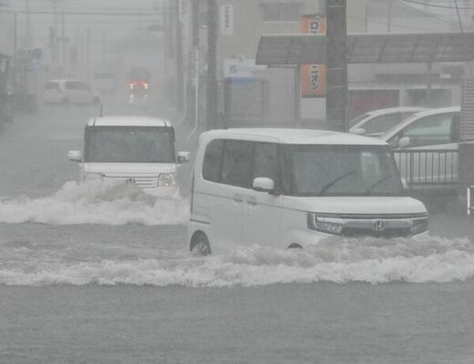 冠水した交差点を慎重に進む乗用車＝４日午後１時５分、宇都宮市横田新町