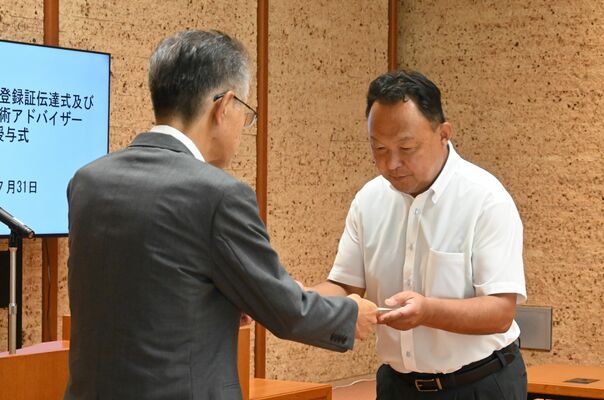 災害復旧技術専門家の登録証を受け取る元県職員（右）＝31日午後、県公館