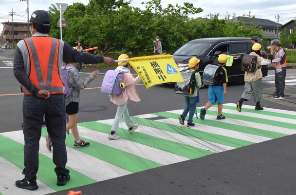 登校する児童の見守り活動を行う従業員ら