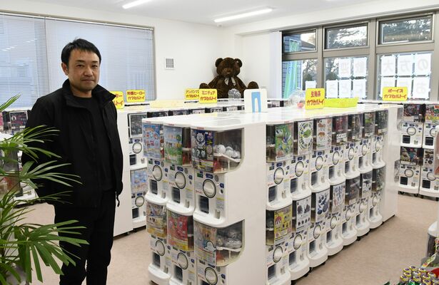 ２００種のカプセルトイが並ぶ店内と舘野社長＝下野市石橋