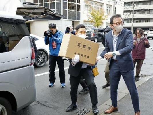 「サクセス観光」事務所からの押収物を運ぶ北海道警の捜査員=23日、札幌市中央区