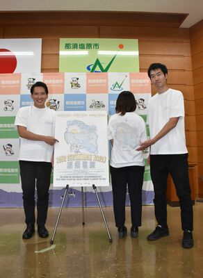 「２０５０　サステナブルビジョン」のポスターとＴシャツを紹介する渡辺市長（左）ら