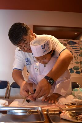 真剣な表情でアジをさばく小学生たち