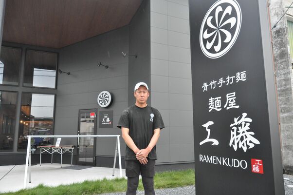 モダンな新築の店舗の前に立つ店主の工藤さん