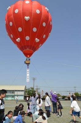 気球に向かって手を振る児童ら