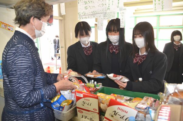 松島高の売店で大山さん（左）からパンを買う生徒たち＝４月20日