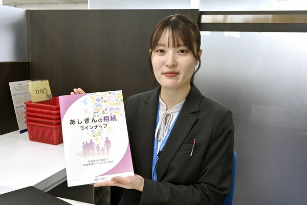 社内副業で制作に携わったパンフレットを手にする小松さん＝７月上旬、宇都宮市