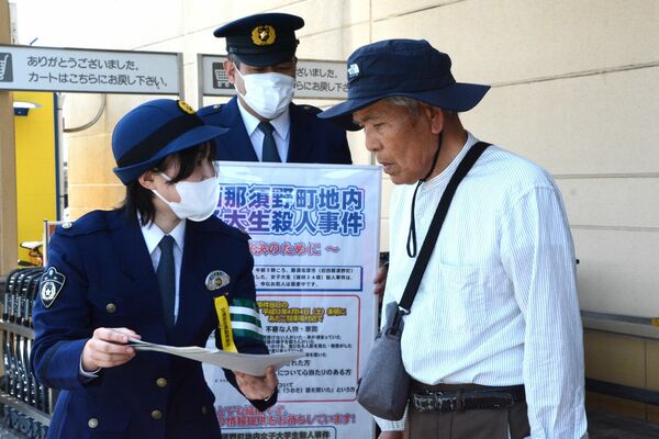 事件概要などが書かれたチラシを配って情報提供を呼び掛ける那須塩原署員ら＝14日午前10時55分、那須塩原市太夫塚６丁目