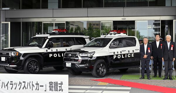中村さん（左）が寄贈したパトカー仕様の（左から）トヨタ「ランドクルーザー」と「ハイラックス」＝15日午後１時40分、県庁、