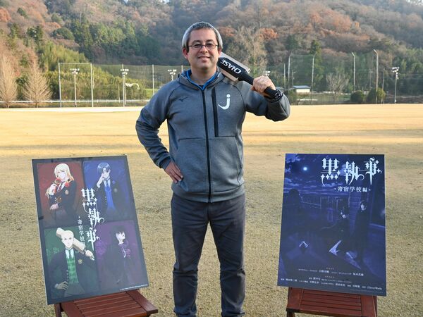 ポスターと並んでキャラクターと同じポーズをとる宮地さん