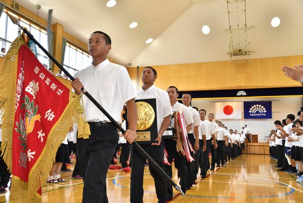 拍手を受けながら甲子園への決意を高める青藍泰斗ナイン＝同校創立百周年記念会堂