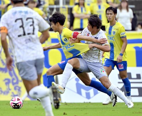 前半26分、相手と激しく競り合う栃木ＳＣのＭＦ佐藤（左から２人目）＝県グリーンスタジアム