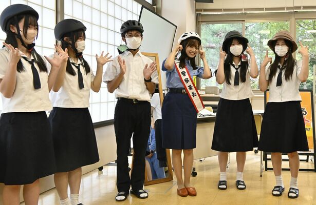 一日警察署長を委嘱され、母校の在校生とヘルメットを試着する菊池さん（中央右）