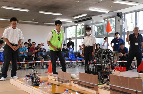 真剣な表情でロボットを操作する高校生ら