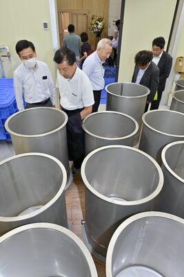 小林醸造の酒蔵で使用する仕込み用タンクを見学する関係者＝４日午後、鹿沼市上粕尾