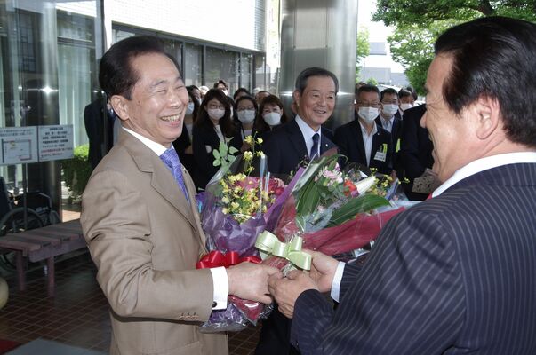 花束を受け取り笑顔を見せる見目町長（左）と古谷副町長（中央）