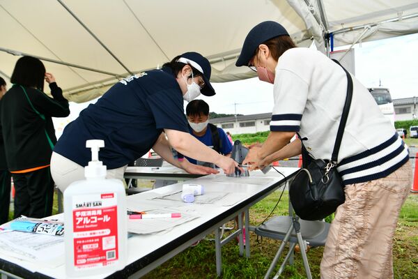 会期前競技の入場口で体調管理チェックシートを確認する係員（左）。国体・障スポ各会場で感染対策が取られた＝９月10日午前、足利市内