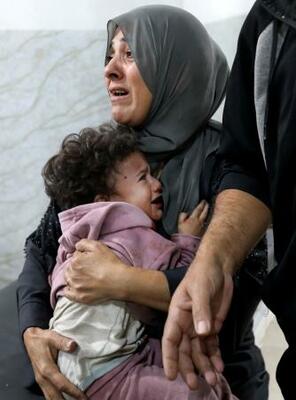 イスラエル軍の攻撃を受けた後、医療処置を受けたパレスチナ人の母子=22日、ガザ(ロイター=共同)