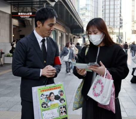吉川友梨さんの情報提供を呼びかける大阪府警の警察官(左)=20日午後、大阪・難波