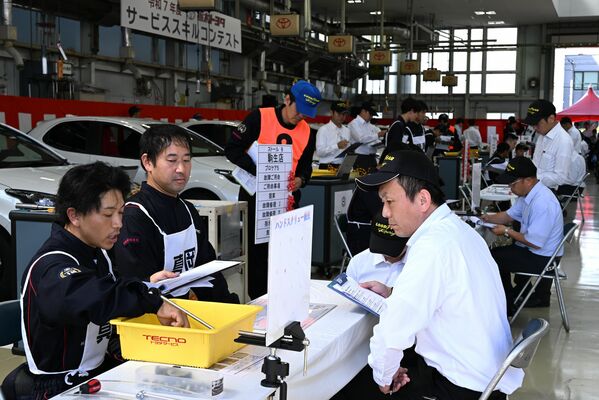 顧客役の審査員に整備内容を説明するゼッケンを着けた出場者＝22日午前、宇都宮市