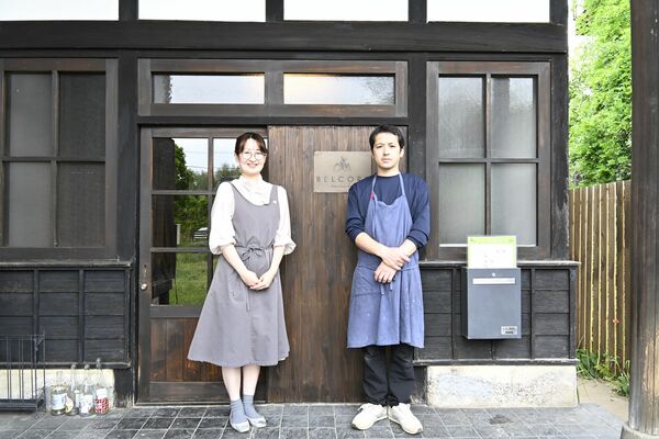 入り口に立つ店主の川原井丈之さん（右）。左は妻の静香さん