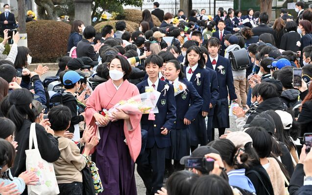 在校生らがつくる花道を恩師と一緒に歩く卒業生＝17日午前11時45分、大田原市市野沢小