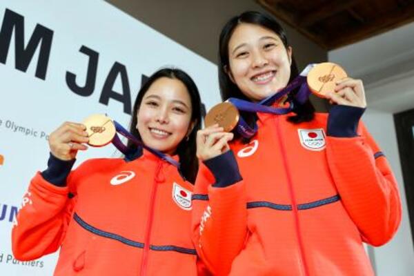 記者会見でメダルを掲げるノルディックスキー・ジャンプ女子の高梨沙羅(左)と丸山希=16日、イタリア・ミラノ(共同)