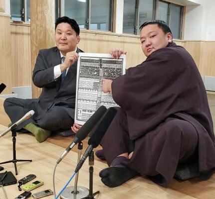 　大相撲初場所の番付表を手にする朝白龍。左は高砂親方＝２２日、東京都墨田区の高砂部屋