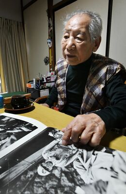 白黒の写真を見ながら、あの頃を振り返る浅見さん。懐かしい顔が並ぶ＝２０２２年12月中旬、日光市足尾地域