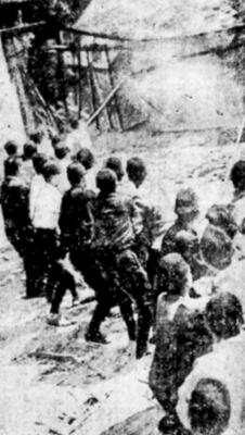 建物の取り壊しに協力する警察官。柱につなげた綱を引いているとみられる（１９４５年４月１３日付京都新聞から）