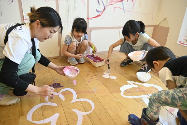 モデルハウスの床に自由に絵を描く子どもたち