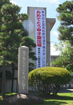 校訓の石碑の後ろに甲子園出場を祝う懸垂幕がなびく石橋高