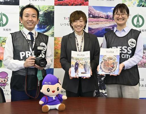 広報紙部門で総務大臣賞に選ばれた広報やいた昨年１２月号（中央）と写真部門で入選した同３月号（右）を担当した市秘書広報課の３人