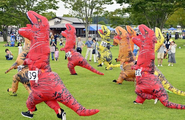 恐竜の着ぐるみを着て全力疾走する出場者たち＝15日午前10時50分、大田原市佐良土