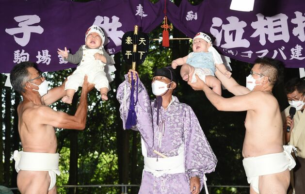 力士役の氏子に掲げられ泣き声を上げる子どもたち＝２５日午後０時２０分、鹿沼市樅山町